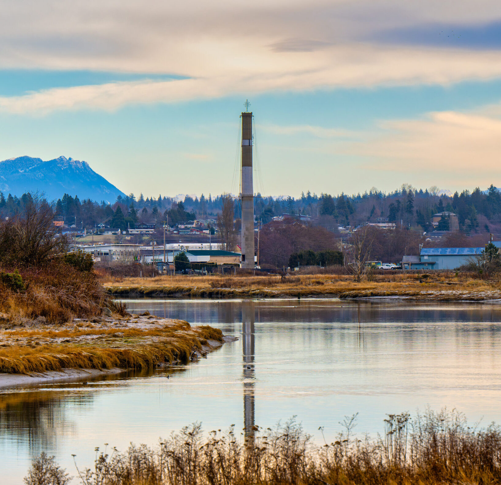 2022-12-04 THE STILLAGUAMISH RIVER WINDING THROUGH STANWOOD WASHINGTON WITH A SMOKE STACK AND BUILDINGS IN THE BACKGROUND NEAR CAMANO ISLAND WASHINGTON