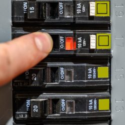 Finger resetting a tripped breaker in residential house electric box