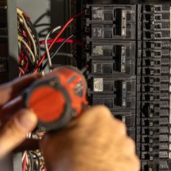 Electrician is installing an electrical circuit breaker in a power panel using a screwdriver. Selective focus